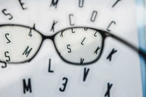 Floating letters in background with pair of black spectacles in foreground