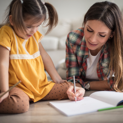 A parent and young child practice writing at home.