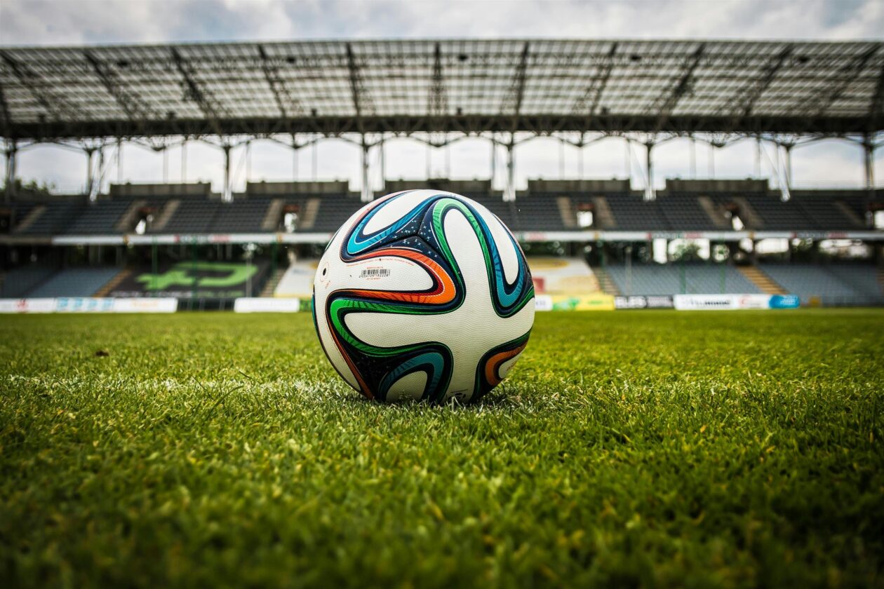A football on a football pitch. Photo by Pixabay: https://www.pexels.com/photo/multicolored-soccer-ball-on-green-field-47730/