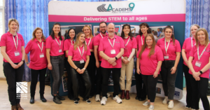 Picture of Academy9 volunteers wearing pink shirts. There are several men and women standing in front of an Academy9 banner.
