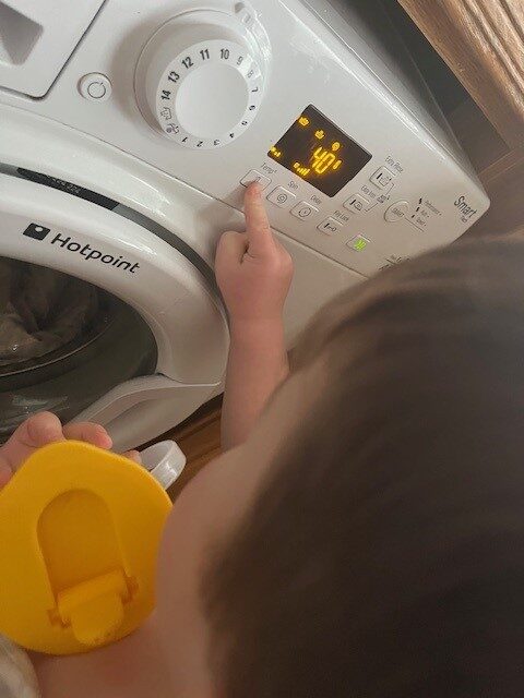 image of a toddler pressing the buttons on the LED panel of a washing machine