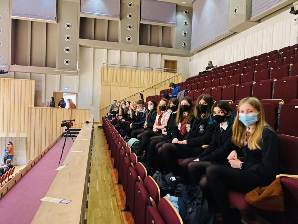 A row of pupils wearing face masks, sitting in the audience of a concert hall.