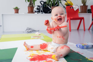 Photo of smiling baby messy with paint