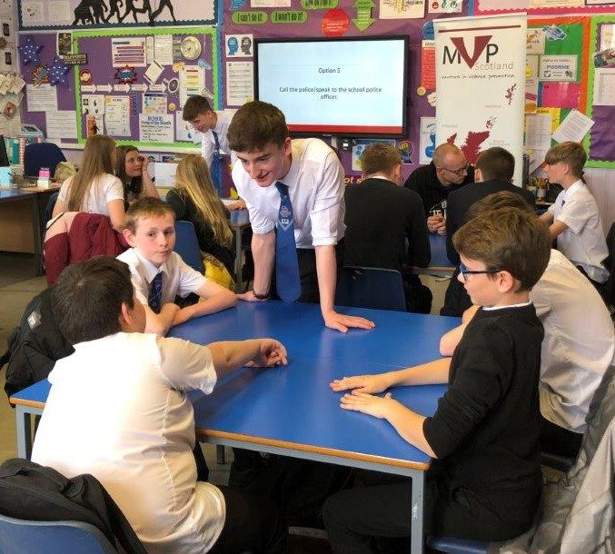 Older learner talking to 4 younger pupils