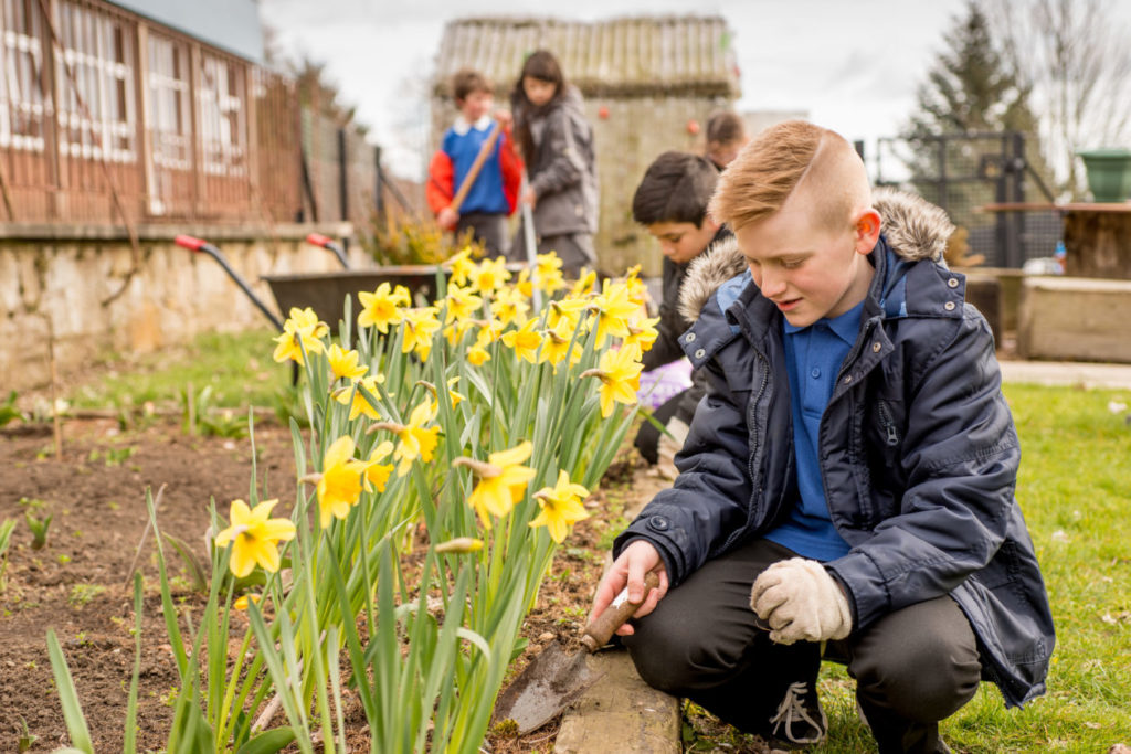 This image depicts young people playing outside during a gardening projects.