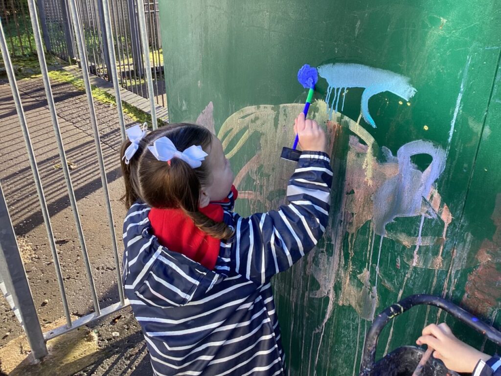 Child making marks with paint brushes.