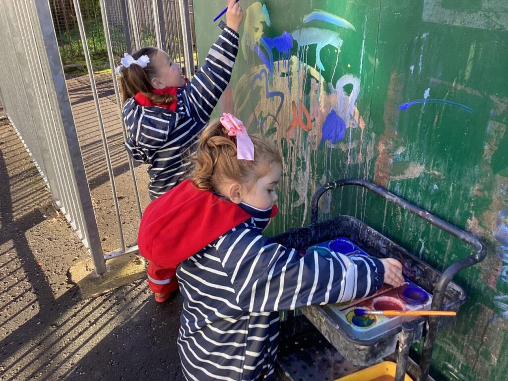 Child making marks with paint brushes.