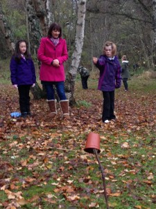 Morgan, Mrs Owen and Nicola try to hit the flower pot with pine cones