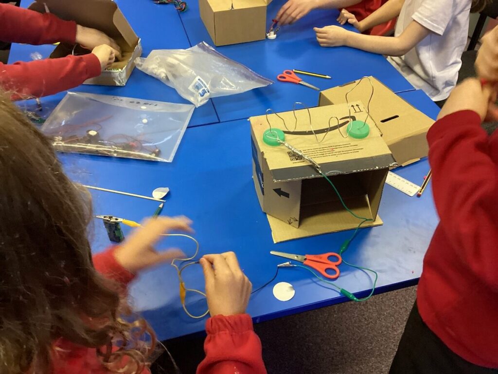 Children working on making a steady hand game with wire & cardboard boxes