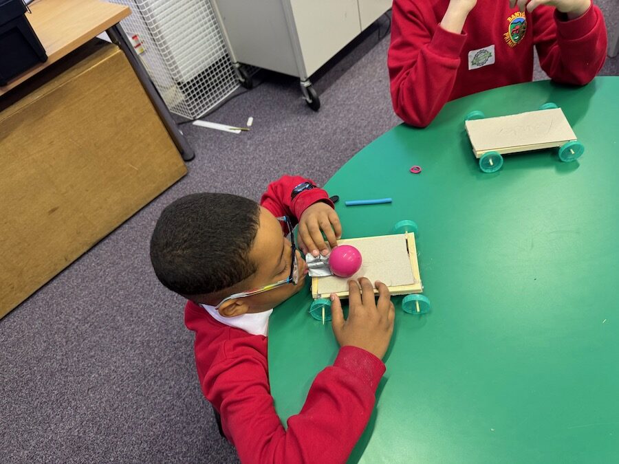 two children working on model balloon cars