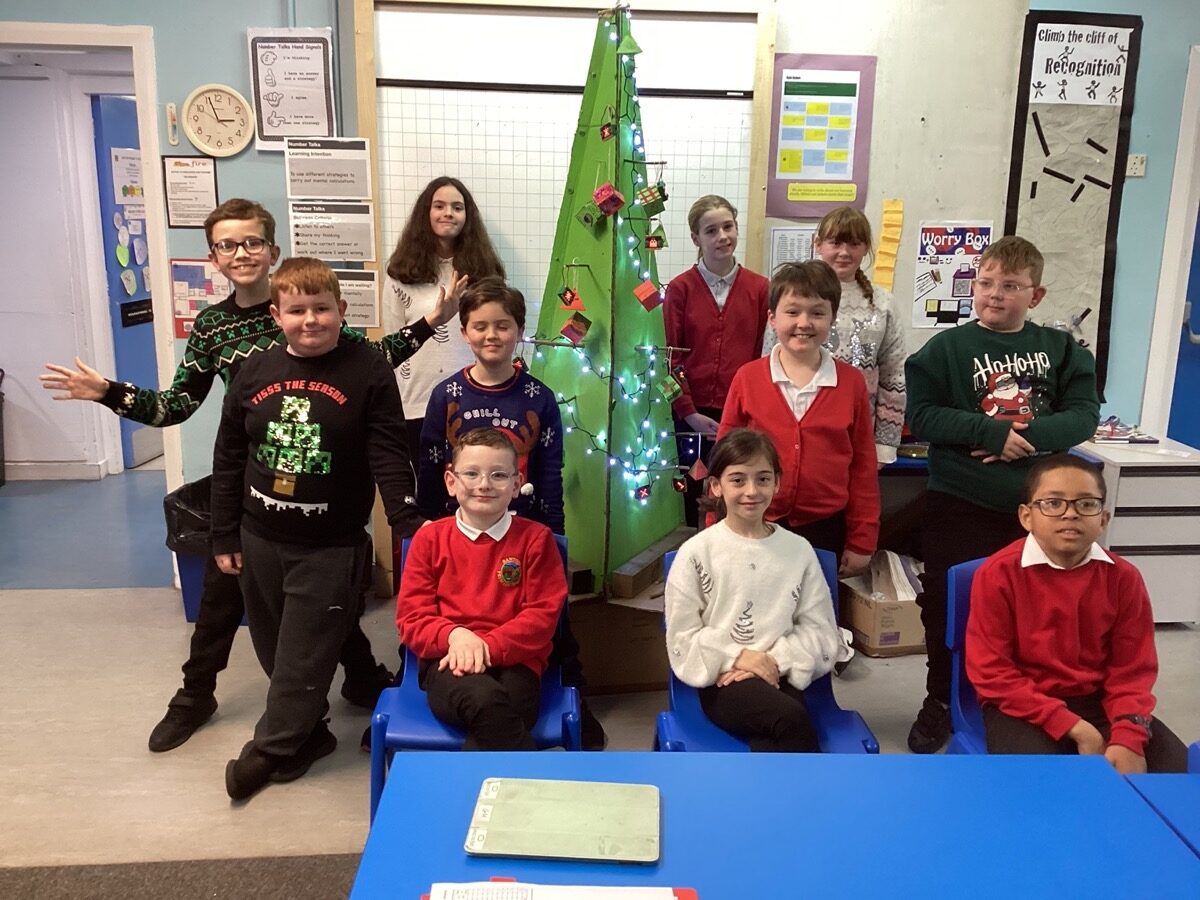 Children gather round a cardboard christmas tree